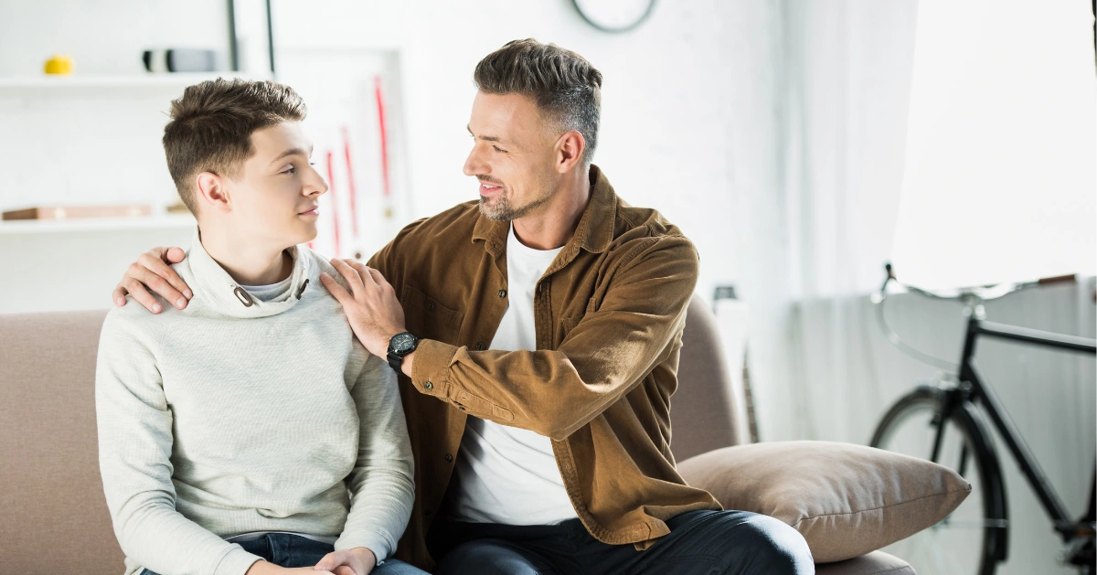 Teen boy sitting on the couch with his dad