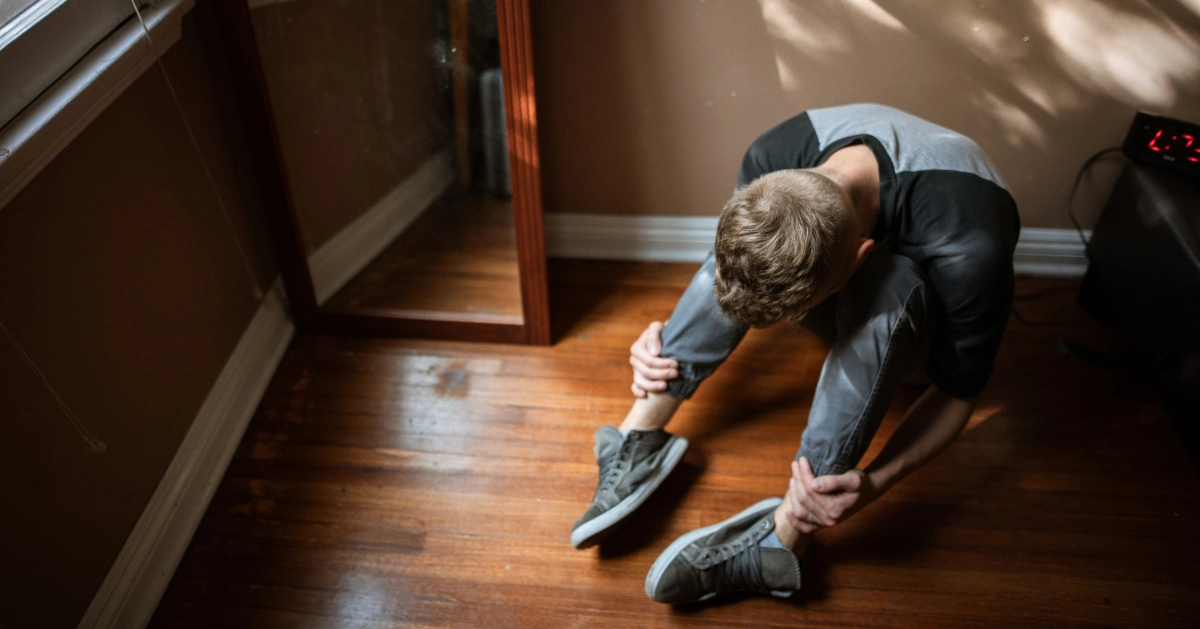 Guy sitting on the floor with his head down.
