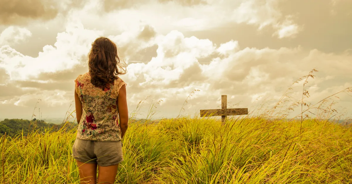 a girl standing in front of a cross