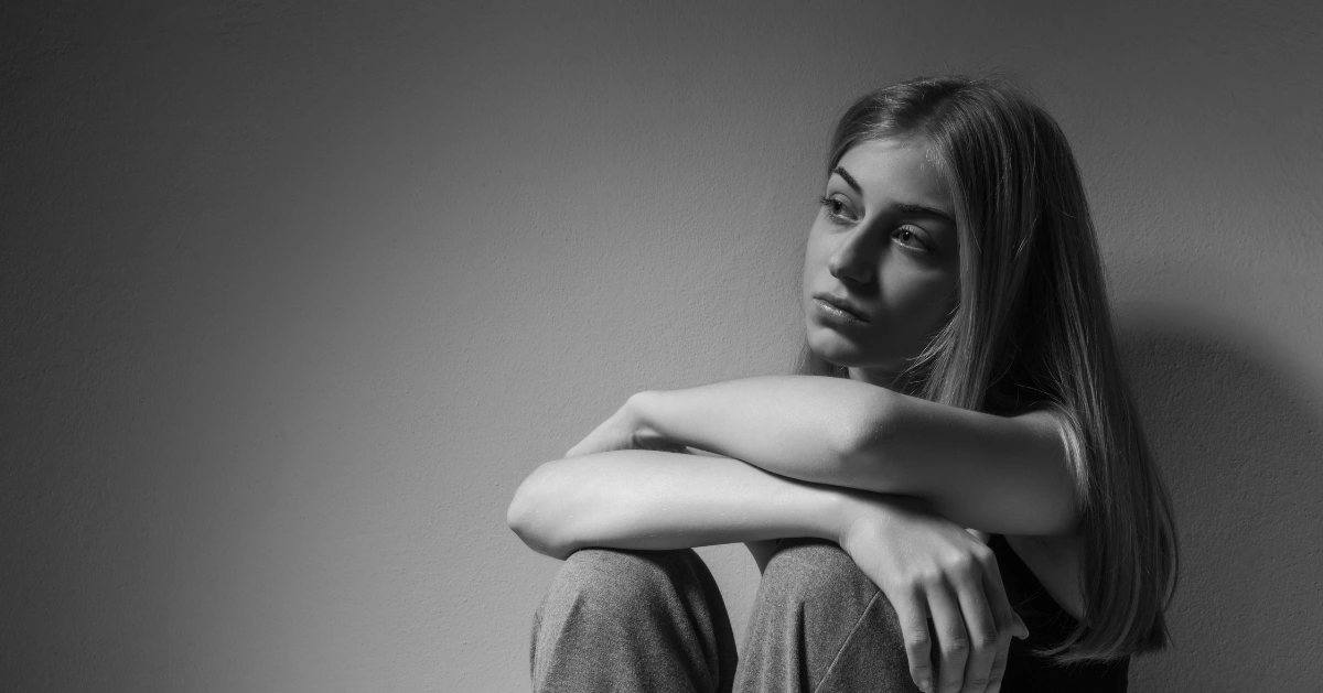 a girl sitting on the floor in deep thought