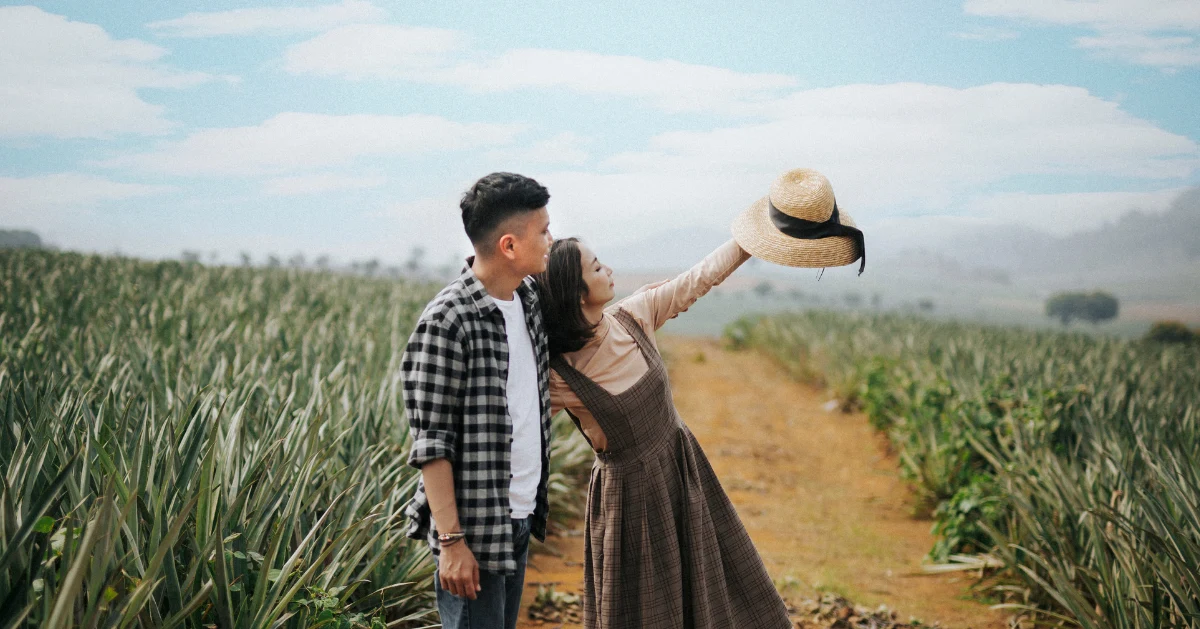 A couple holding up a hat outside.
