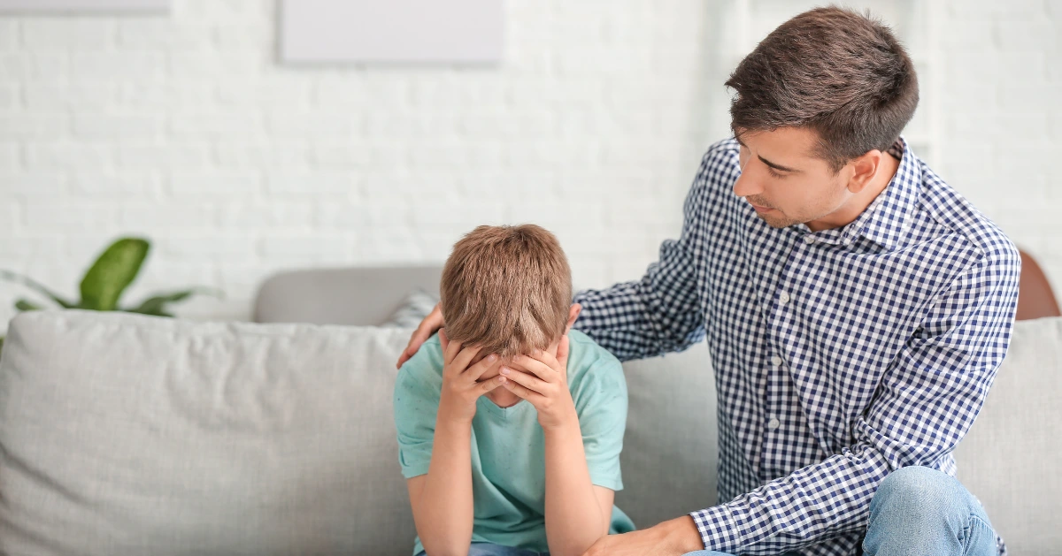 a young boy on the couch with his parent comforting him