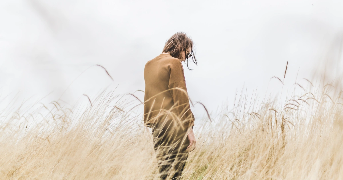 a man standing in a field with his head down