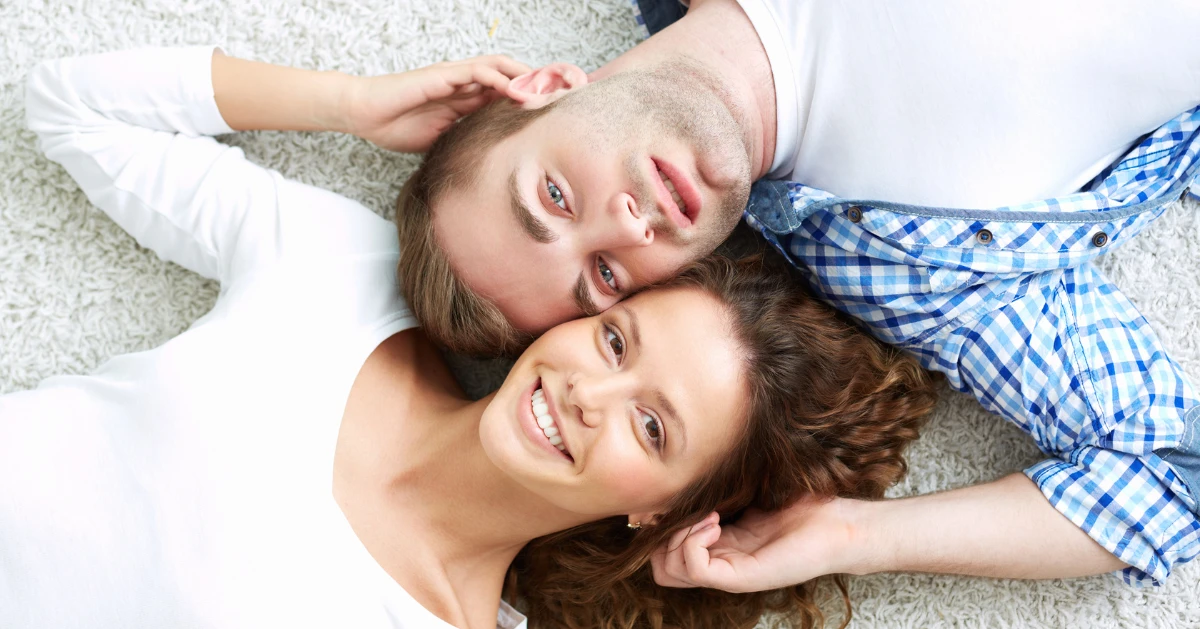 a couple lying on the floor looking at the camera smiling