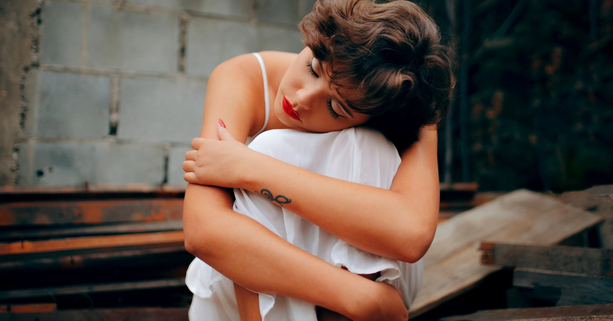 a girl sitting on the ground hugging her legs