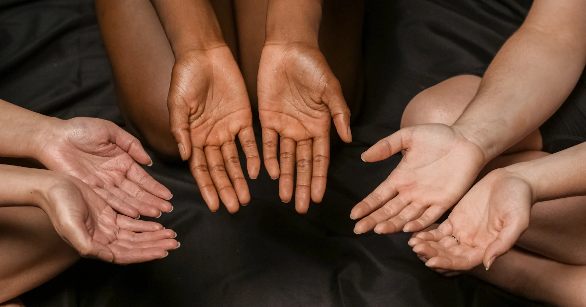Three people with different races holding their hands out in a circle.