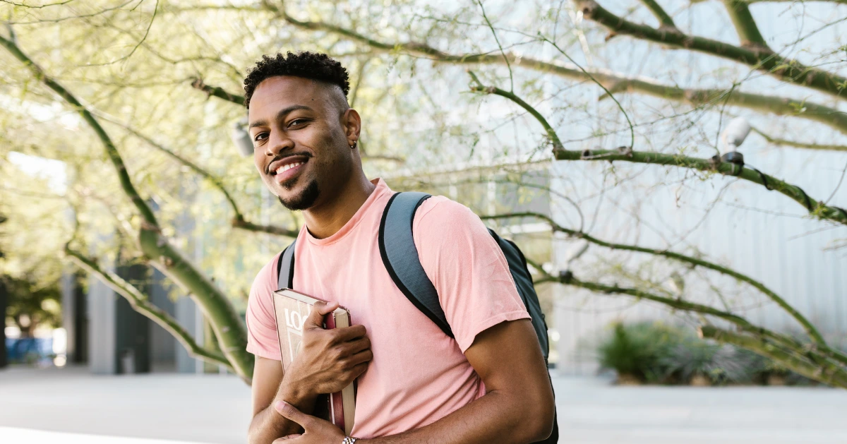 young black man smiling and holding a book