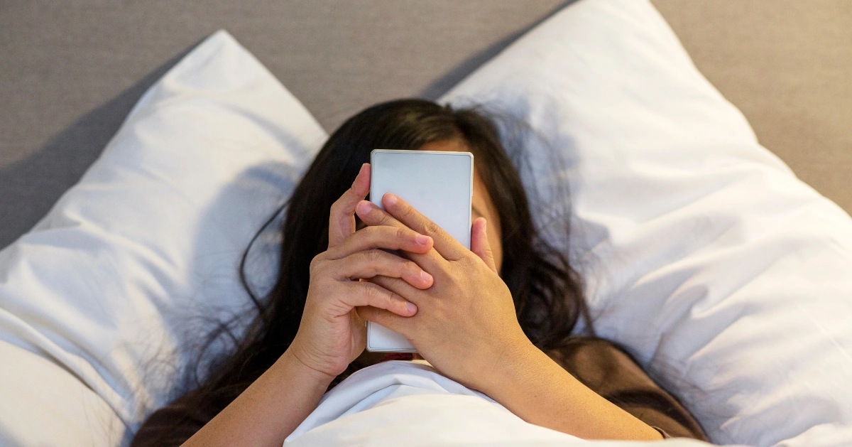 Woman in bed on her phone